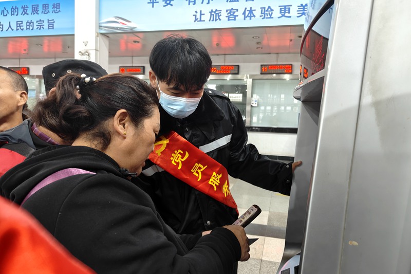 在海口站，志愿者幫助旅客購票。唐璐璐攝