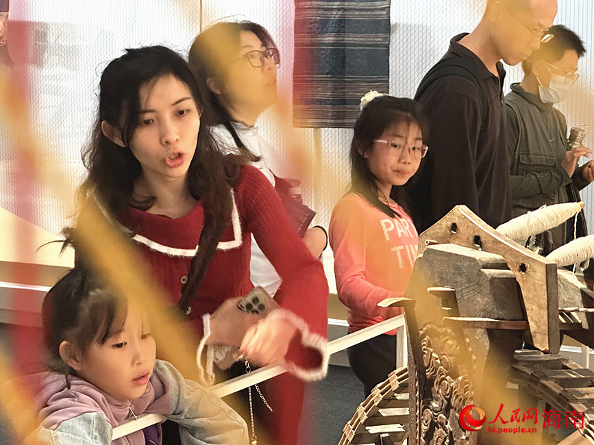 家長對應著墻畫上的示意圖，為孩子講解展品背后的故事。人民網 劉楊攝