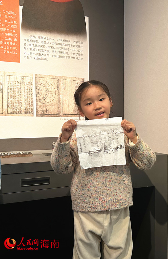 小女孩展示剛剛通過雕版印刷互動裝置獲得的拓印宣紙。人民網 劉楊攝