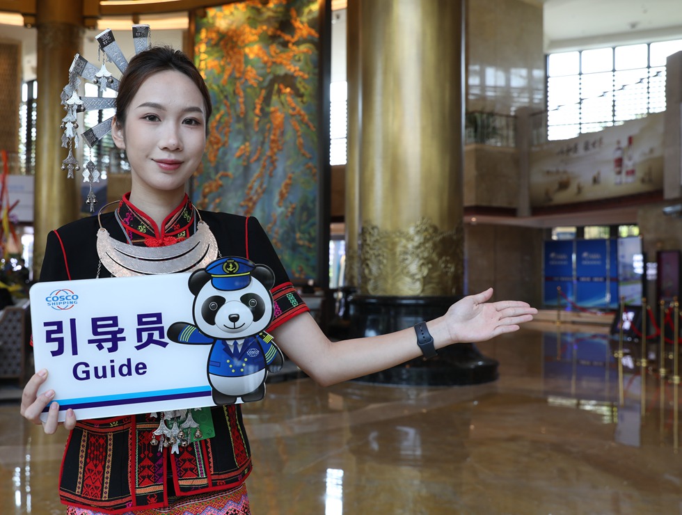 身穿黎族服裝的引導員在論壇現場給來賓做引導