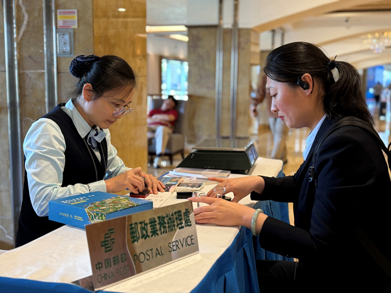 海南郵政工作人員為來自北京的論壇嘉賓肖女士提供蓋戳服務(wù)。陳師攝