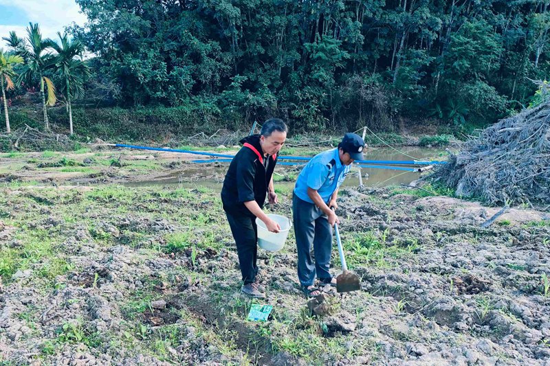 范平釗（左一）幫助農戶鋤地。育才生態區馬腳村委會供圖.jpg