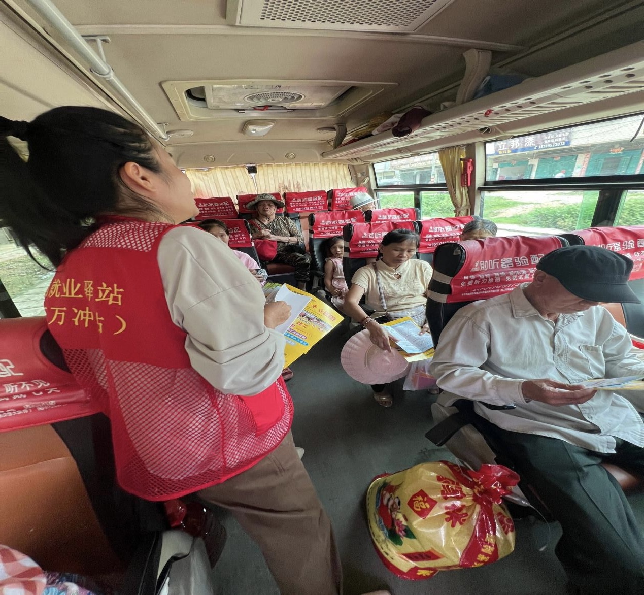 驛站工作人員在大巴車上為村民介紹招聘崗位。萬沖就業驛站供圖